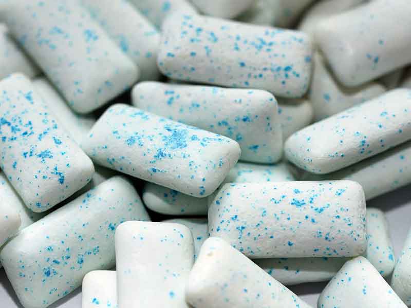 Many small chewing gum with blue dots, made from gum base